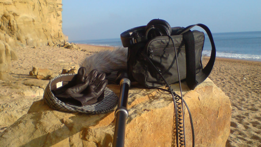 field recording equipment on a beach with golden sand and blue sky